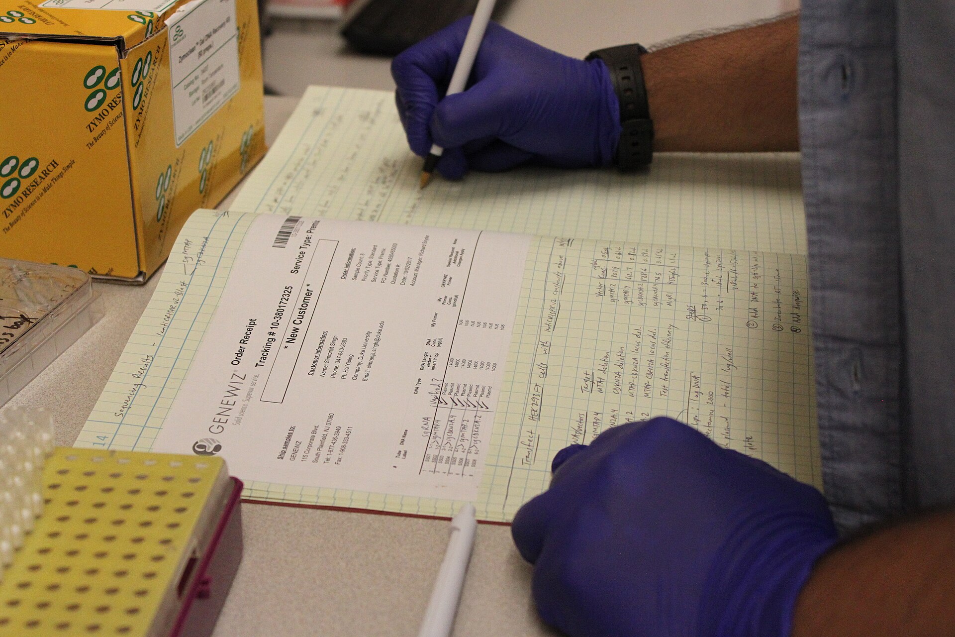 A researcher writing notes by hand in a laboratory notebook.